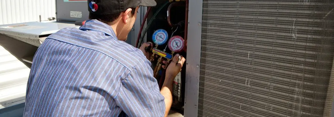 HVAC technician servicing a condenser unit in Bedford