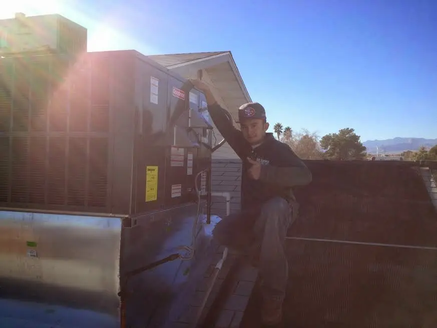 HVAC technician performing Air Duct Cleaning on a rooftop unit in Bedford
